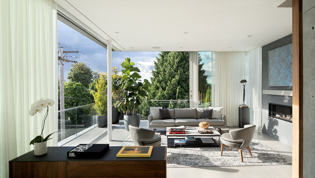 Spacious modern living room with large windows, plush seating, and lush greenery outside.