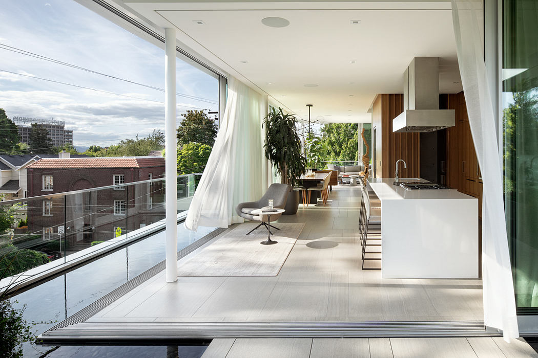 Airy, modern living space with sleek glass walls, minimalist furnishings, and greenery.