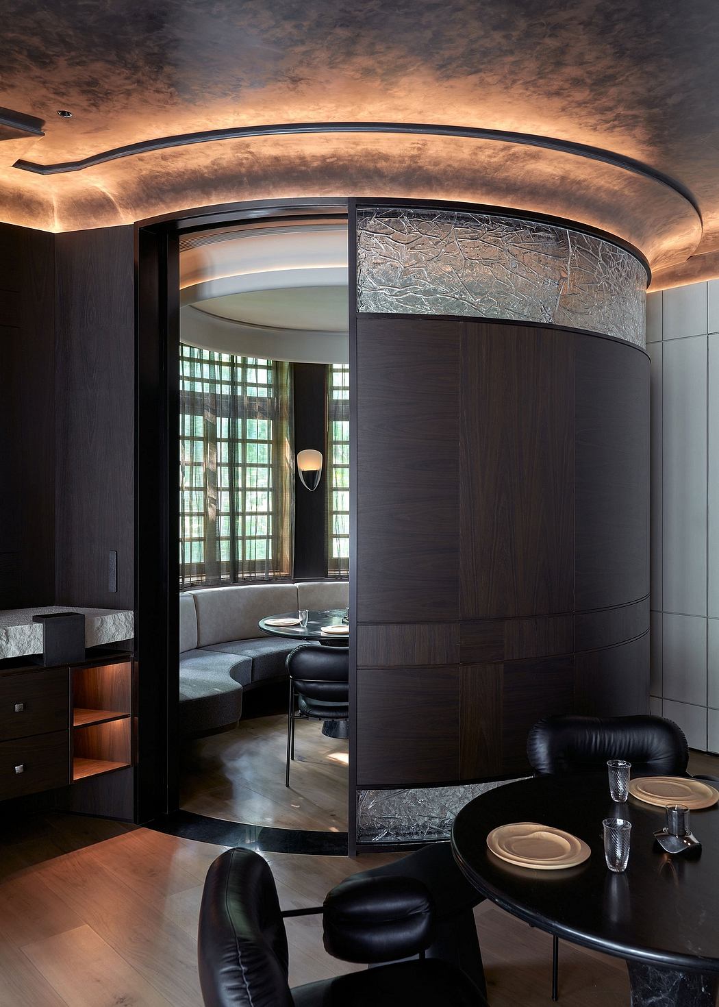 Striking curved architectural elements, layered textures, and luxurious seating create an elegant, modern ambiance.