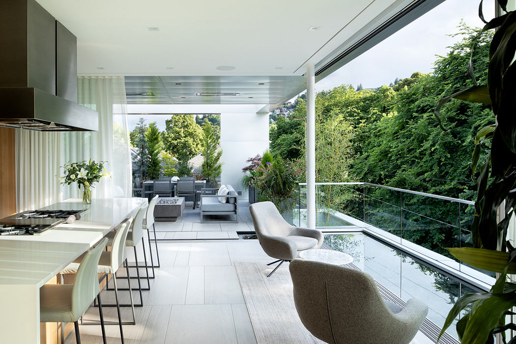 Modern kitchen and living space with large windows overlooking lush greenery.