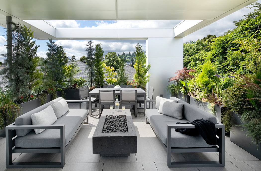 Elegant modern patio with sleek gray seating, outdoor dining, and lush greenery.