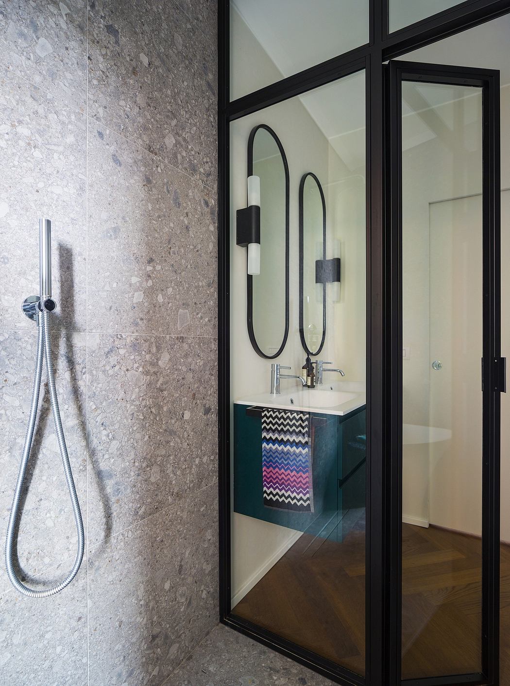 Sleek modern bathroom with black metal framed mirrors, vanity, and tiled walls.