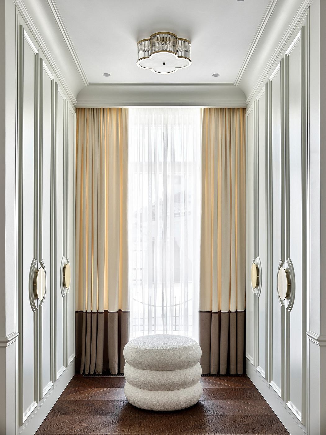 Elegant entryway with intricate molding, opulent chandelier, and custom drapery panels.