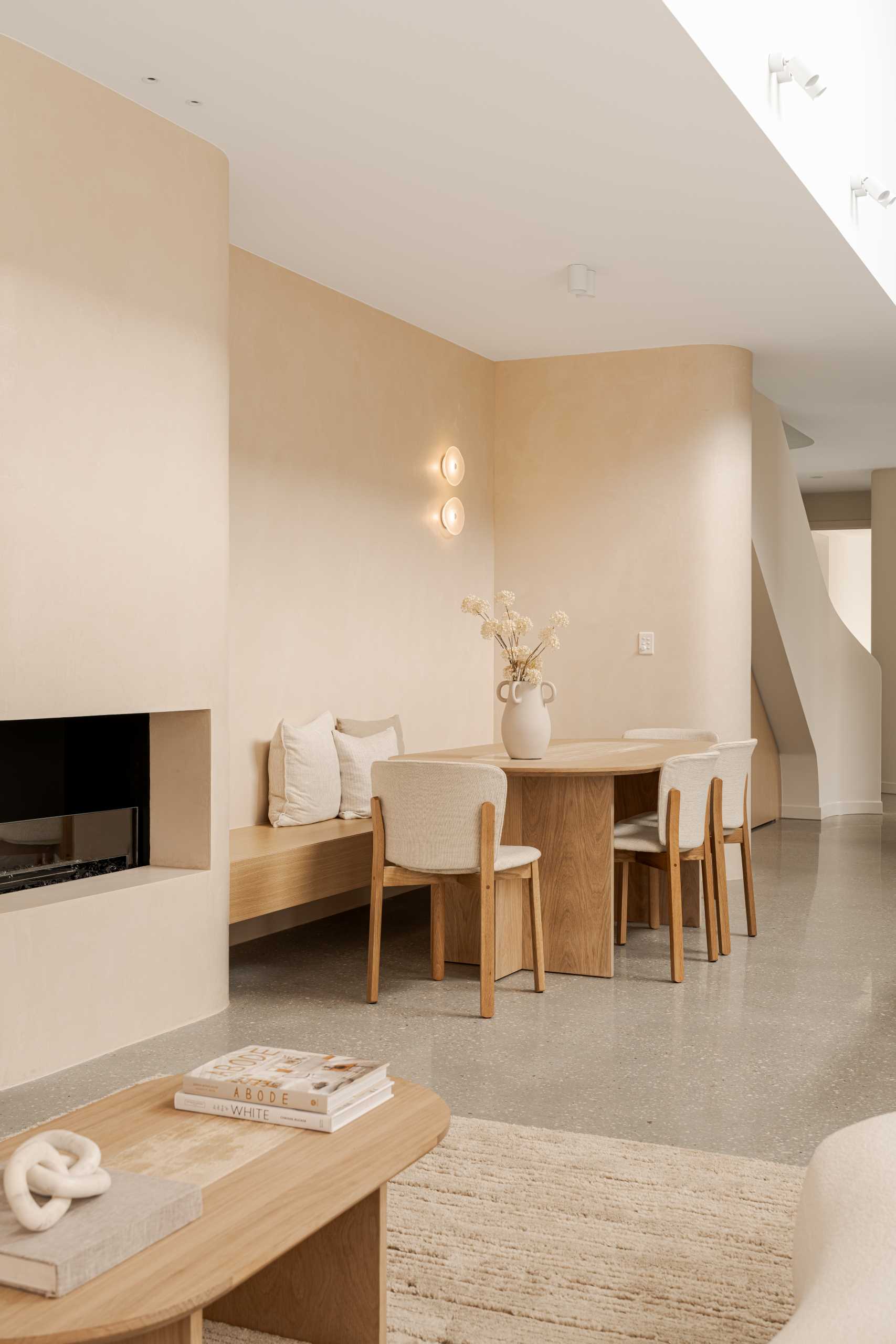 This dining room includes built-in wood banquette seating and a dining table with rounded corners.