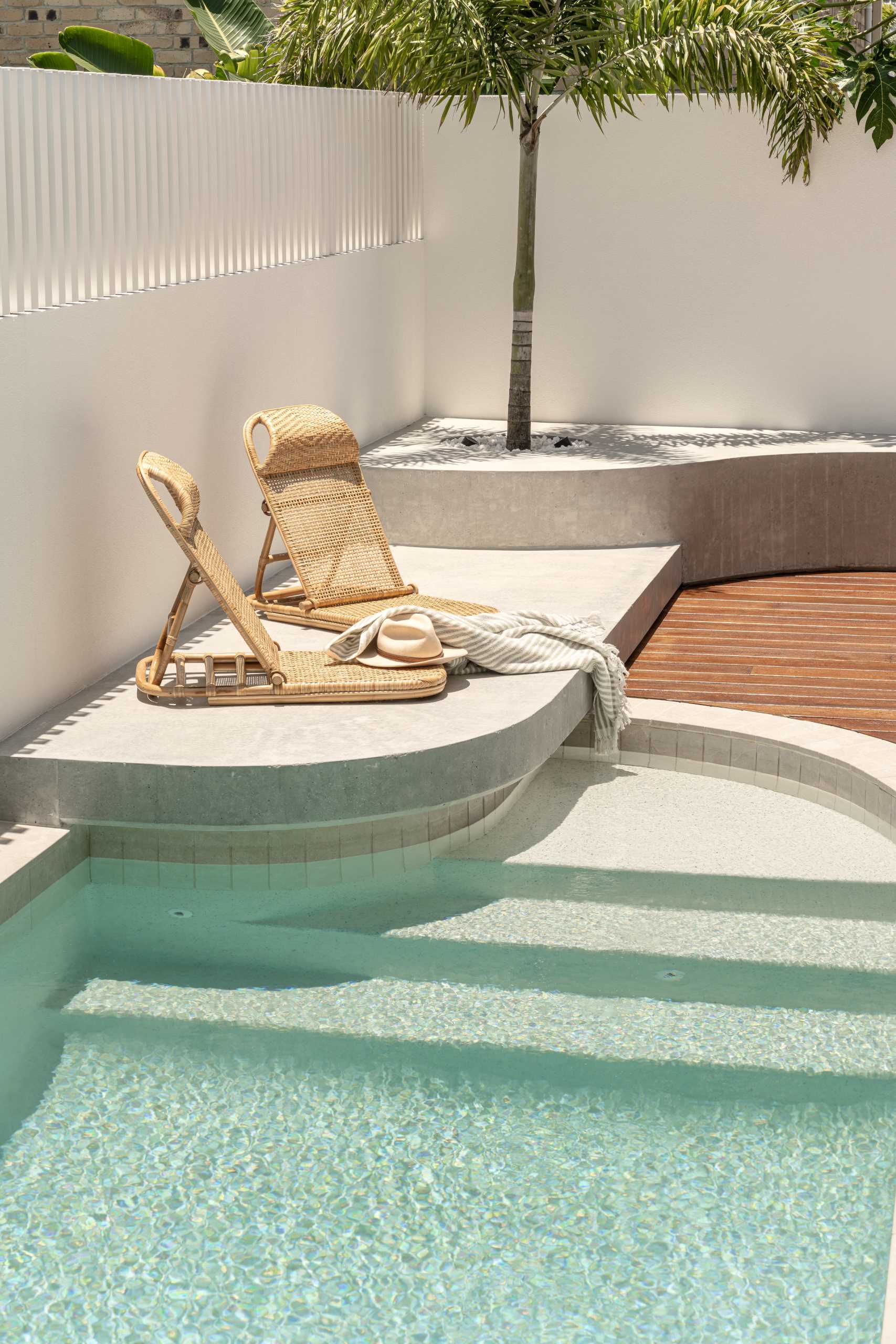 A swimming pool with a wood deck and a raised platform for lounging in the sun.