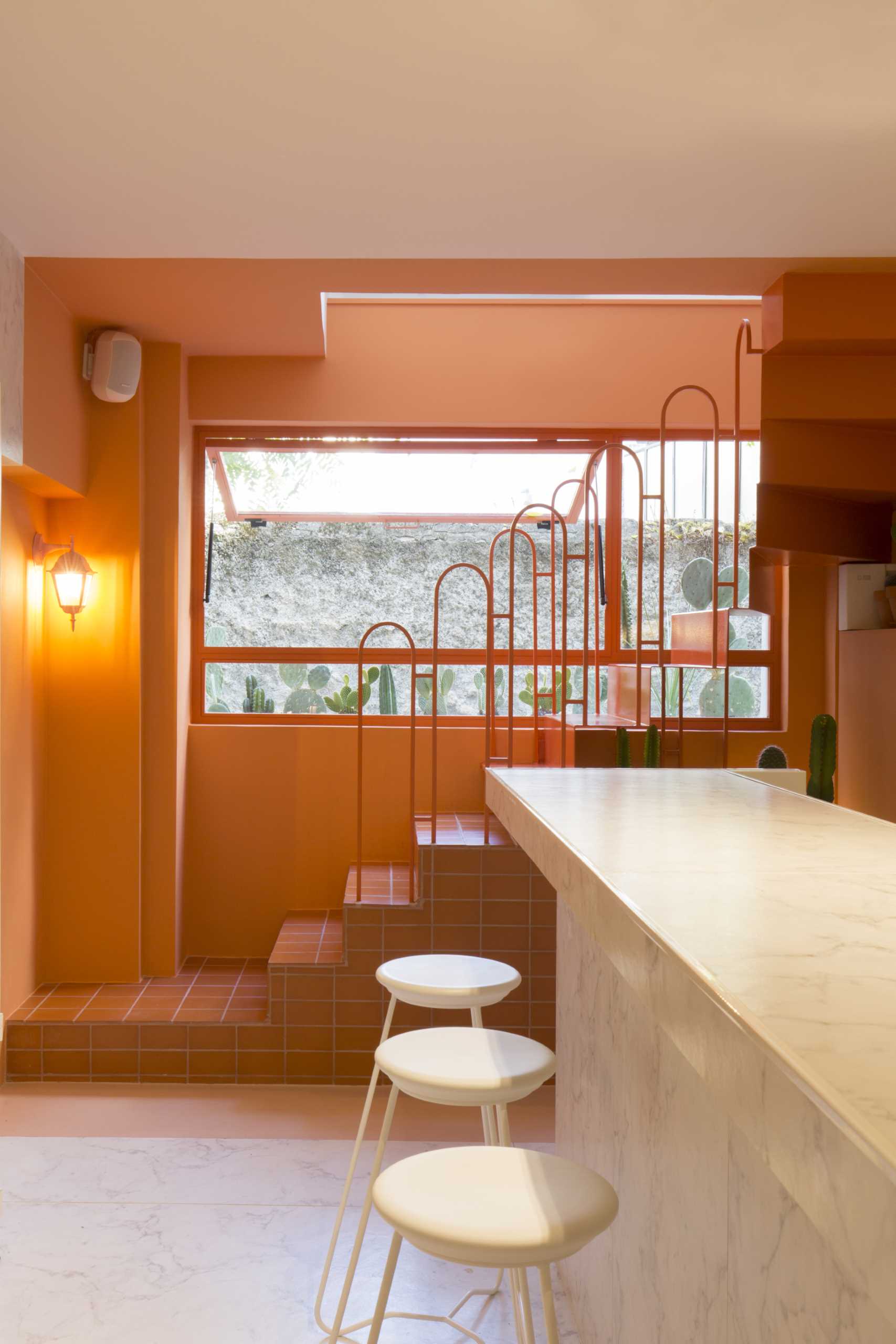 A modern retail store with a monochromatic terracotta interior that also includes built-in planters for cacti.