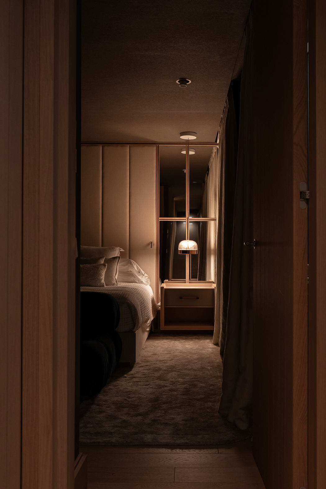 Cozy bedroom hallway with warm lighting, wood paneling, and plush carpeting.